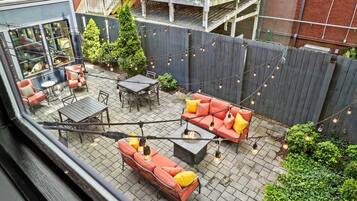 Een terras op het dak met buitenmeubilair, een vuurkorf en lichtslingers.