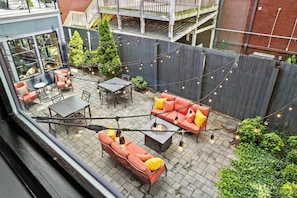 A rooftop patio with outdoor furniture, a fire pit, and string lights. - The Roosevelt Suite | Germantown Inn | Breakfast (Nashville)