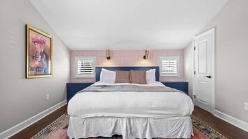 Een slaapkamer met een groot bed, twee wandlampen, een deur en een vloerkleed met een patroon.