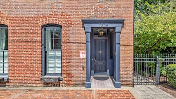A brick building with a dark blue entrance door, a small window, and a sign indicating a fire department connection.