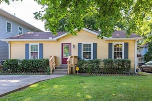 A single-story house with a front porch, a red door, and a small front yard. - 3BR Cottage - 3 Miles to Downtown (Nashville)