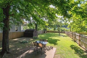 A backyard with a table and chairs, a grill, and a wooden fence. - 3BR Cottage - 3 Miles to Downtown (Nashville)