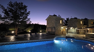 Un edificio de piedra con piscina al anochecer.