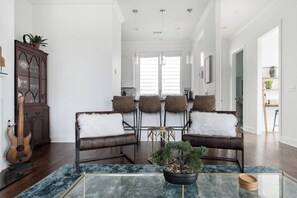 A spacious living room with a glass coffee table, leather sofas, and a dining area with chairs. - East Nash Stay Near Hotspots (Nashville)
