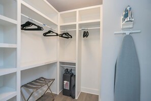 Un dressing avec des étagères, un étendoir et une planche à repasser.
