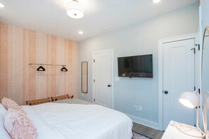 A bedroom with a bed, a TV mounted on the wall, and a door with a mirror. - Chic 3BR + Free 2-Car Garage | Near Downtown (Nashville)
