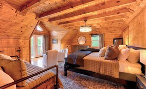 A wooden cabin interior with a bed, a chair, and a small table. - 5 BR Luxury Cabin | Pool, Hot Tub & Game Room (Franklin)