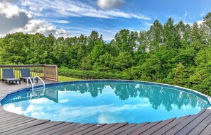 Ein Pool mit Holzterrasse, umgeben von üppigen, grünen Bäumen.