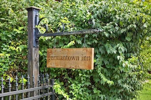 A sign for Germantown Inn, mounted on a metal post with a chain, surrounded by dense foliage. - The Adams Suite | Germantown Inn | Breakfast (Nashville)