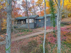 A cabin with a wooden exterior, a covered porch, and a pathway leading to the entrance. - 65Acres HotTub, Sauna, Cold Plunge, Fishing + Golf (Joelton)