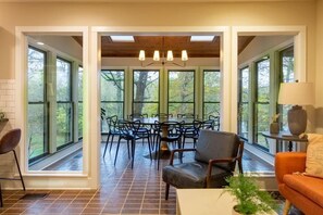A dining area with a table and chairs, large windows, and a ceiling with skylights. - 65Acres HotTub, Sauna, Cold Plunge, Fishing + Golf (Joelton)