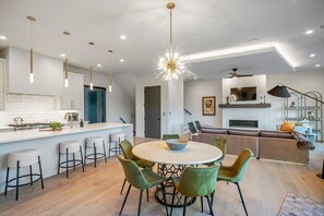 Une cuisine moderne dotée d’un îlot central, de tabourets de bar et de luminaires suspendus.