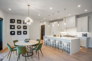 A modern kitchen with a central island, bar stools, and pendant lighting. - 30 Night + Luxurious Green Hills Gem! (Nashville)