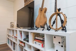 A white entertainment unit with a TV, a wooden guitar, and a telescope. - Elegant Farmhouse 15 Min to Nashville (Nashville)