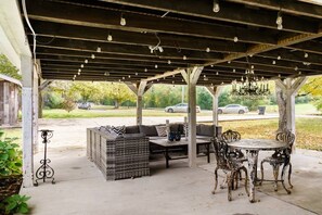 An outdoor covered patio with seating, a table, and hanging lights. - Elegant Farmhouse 15 Min to Nashville (Nashville)