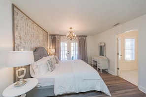 A bedroom with a large bed, bedside tables, a dresser, and a chandelier. - Elegant Farmhouse 15 Min to Nashville (Nashville)