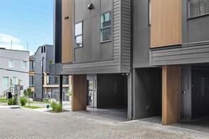 Un bâtiment moderne à plusieurs étages, doté d’un toit plat, de grandes fenêtres et d’un espace d’entrée pavé.