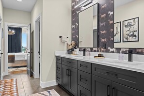 Een moderne badkamer met een grote spiegel, donkere kastjes en decoratieve wandkunst.