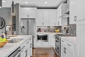 A modern kitchen with white cabinets, stainless steel appliances, and a herringbone-patterned backsplash. - Rooftop Oasis - Hot Tub, Nashville City Views (Nashville)