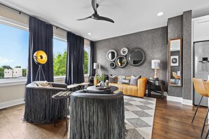 Een moderne woonkamer met een bank, twee fauteuils, een salontafel en een plafondventilator.