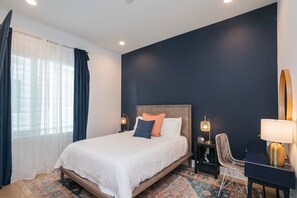 Ein Hotelzimmer mit Bett, Nachttischen, einem Sessel und einem Schreibtisch.