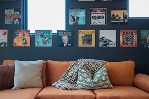 Ein Zimmer mit einem braunen Ledersofa und einer Wand, die mit verschiedenen Schallplattenhüllen verziert ist.