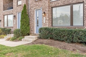 A two-story brick building with a blue door, large windows, and a well-maintained hedge. - 2 Homes: 7 Bedrooms Sleeps 22 Walk to WeHo/Geodis (Nashville)