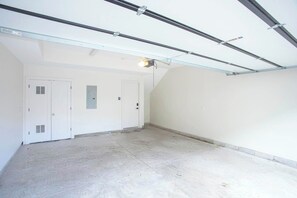 A spacious, empty room with a sloped ceiling and a large door. - 8 Beds Near Broadway | Each Room Has Own Bath (Nashville)