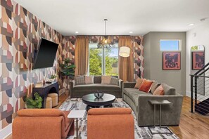 A modern living room with a sofa set, a coffee table, and a flat-screen TV mounted on the wall. - 8 Beds Near Broadway | Each Room Has Own Bath (Nashville)
