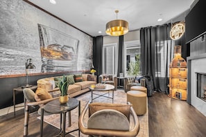 A modern living room with a large abstract painting, a fireplace, and a cozy seating area. - Bourbon & Ballads: Karaoke Stage, Sauna + Rooftop (Nashville)