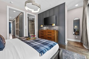 Une chambre à coucher moderne avec un lit, une commode, une télévision et un miroir.