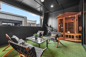A rooftop terrace with a seating area, a small table with a plant, and a wooden structure with shelves. - Bourbon & Ballads: Karaoke Stage, Sauna + Rooftop (Nashville)