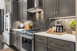 A modern kitchen with stainless steel appliances, a gas stove, and a coffee maker. - Bourbon & Ballads: Karaoke Stage, Sauna + Rooftop (Nashville)
