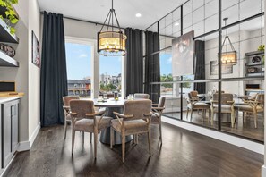 A modern kitchen with a dining area, large windows, and a view of the city. - Bourbon & Ballads: Karaoke Stage, Sauna + Rooftop (Nashville)