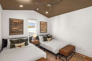 Een slaapkamer met twee bedden, een plafondventilator en kunstwerken aan de muur.
