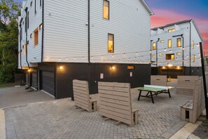 A building with a brick patio, wooden furniture, and string lights. - Prime Spot Minutes to 12 South, Gulch & Broadway (Nashville)