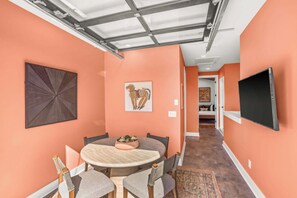 Een eetruimte met een ronde tafel, stoelen en kunstwerken aan de wanden.