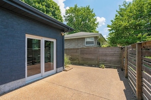 A residential backyard with a patio, a wooden fence, and a house with a brick exterior. - Yard, Parking, 4.5 Mi to Bway (Nashville)