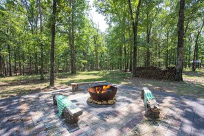 A forested campsite with a fire pit, picnic table, and benches. - Bobwhite at Buckhorn Hollow (McEwen)