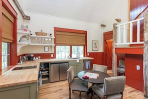 A kitchen with a wooden countertop, a dining table with chairs, and a window with a blind. - Purple Martin and The Cardinal at Buckhorn Hollow (McEwen)