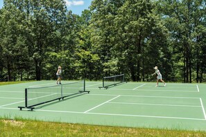 Una cancha de tenis al aire libre rodeada de árboles.