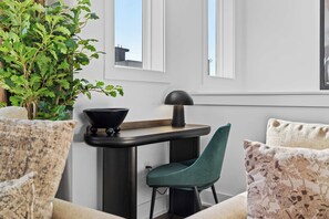 A modern living room with a dark table, teal chair, and a potted plant. - City Views | Rooftop Deck | Fire Pit + Grill (Nashville)