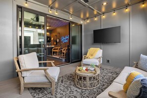 Uma sala de estar moderna com um sofá, cadeiras, uma mesa de centro e uma TV fixada na parede.