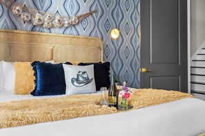 Uma cama com cabeceira texturizada, um objeto decorativo na parede, um abajur e um tapete felpudo.