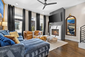 A modern living room with a sofa, armchairs, a fireplace, and a television. - Karaoke Murals Rooftop Parking Near Broadway (Nashville)