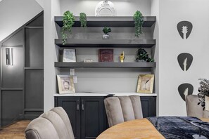 A modern kitchen with dark cabinetry, a built-in oven, and a countertop. There are shelves above the cabinets with plants and decorative items. - Elegant Nash Karaoke Haven w/ Rooftop Fire Table (Nashville)