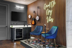 A modern kitchen with a flat-screen TV, two guitars, and a neon sign. - Elegant Nash Karaoke Haven w/ Rooftop Fire Table (Nashville)