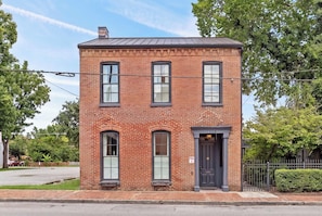 A two-story brick building with a dark entrance door, a small porch, and a clear sky. - The Madison Suite | Germantown Inn | Breakfast (Nashville)