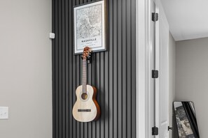 A guitar hanging on a wall with a framed map of Nashville, Tennessee. - Gated Luxury | Broadway Views | Rooftop Fire Pit (Nashville)