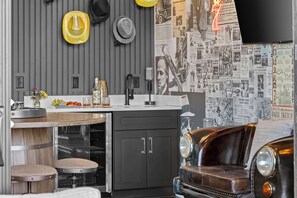 A kitchen with a vintage car, a bar area, and a wall decorated with newspaper clippings. - Gated Luxury | Broadway Views | Rooftop Fire Pit (Nashville)